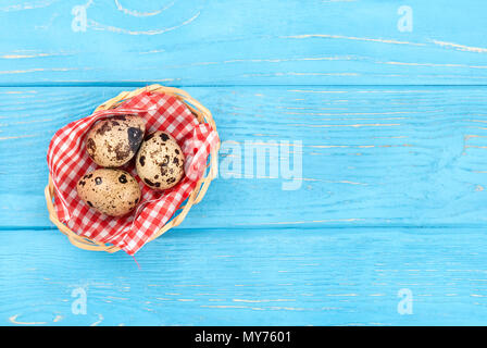 Three fresh quail eggs in a basket on an empty wooden background, top view Stock Photo