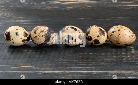 Row of five fresh quail eggs on wooden background Stock Photo