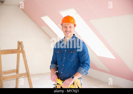 Confident middle aged handyman standing at construction site. Stock Photo