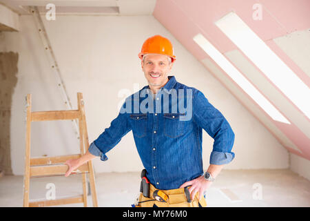 Confident middle aged handyman standing at construction site. Stock Photo