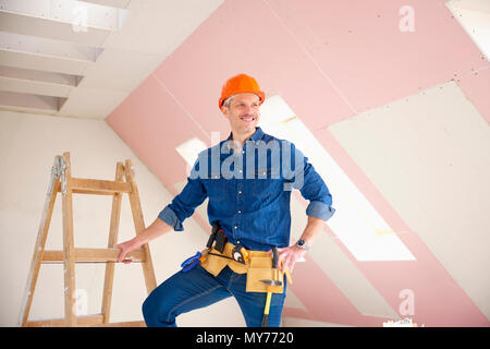 Confident middle aged handyman standing at construction site. Stock Photo