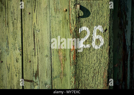 Number 26 with white paint on old green painted wooden door of the old house, a fragment of the facade. The picture was taken in Bulgaria in 2018 Stock Photo