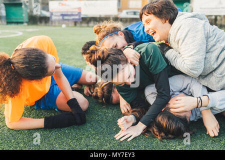 Football players jubilant and hugging on pitch Stock Photo