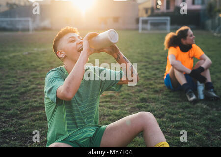 Football players taking break on pitch Stock Photo