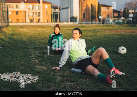 Football players taking break on pitch Stock Photo