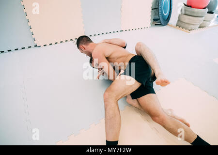 Men on floor in gym wrestling Stock Photo