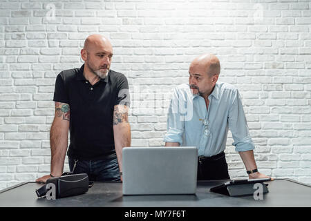 Colleagues with virtual reality headset and laptop having discussion Stock Photo