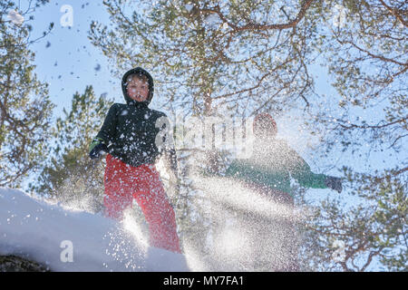 Two boys jumping in snow, low angle view Stock Photo