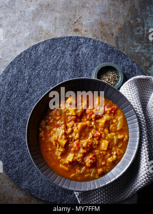Still life with bowl of spicy pumpkin lentil tomato soup, overhead view Stock Photo