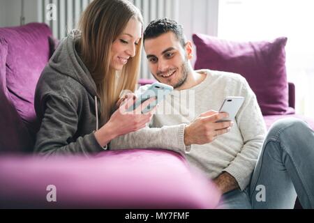 Couple relaxing on sofa using smartphones Stock Photo