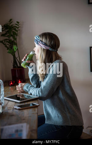 Young woman drinking vegetable juice at cafe window seat Stock Photo