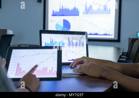 Businessman and woman using screens with graphs and charts in business meeting, close up