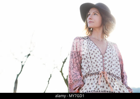 Mid adult woman wearing felt hat against sunlit sky Stock Photo