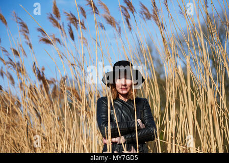 Cool woman wearing felt hat standing among reeds, portrait Stock Photo