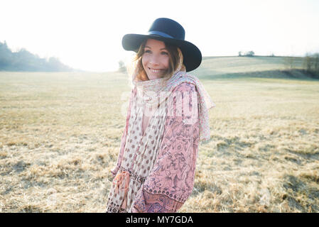 Hippy style woman wearing felt hat in field, portrait Stock Photo