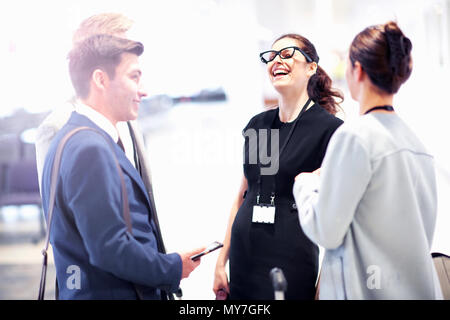 Businessmen and women chatting and laughing in airport Stock Photo