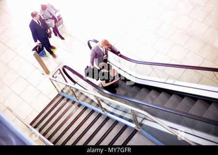 Businessmen and women moving up airport escalator, high angle view Stock Photo