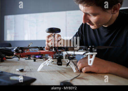 Photo of engineer fixing square copter at table in room Stock Photo