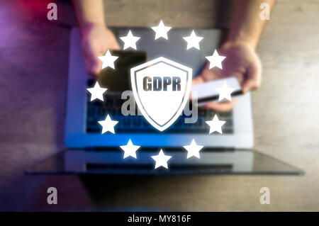 Top view of a blurred manager writing down personal data protection rules for his employees on a wooden table with laptop. GDPR concept Stock Photo