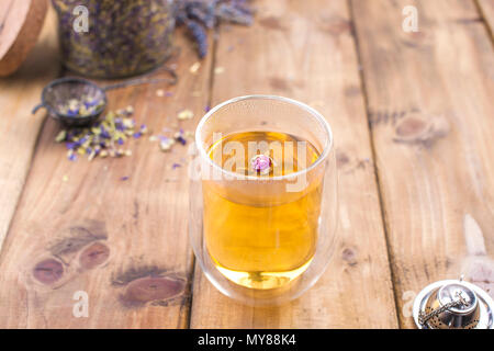A glass with tea, spring white flowers. Bank with honey. Dried tea in a jar. Wooden background and free space for text , copy space Stock Photo