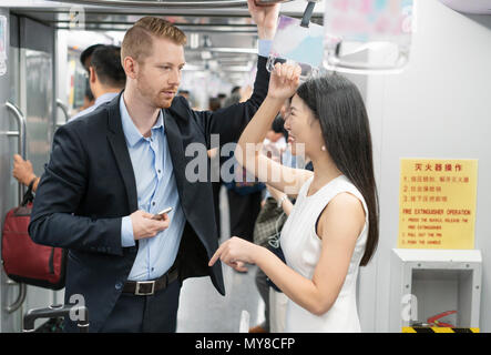 Businessman and woman standing on train, in conversation Stock Photo