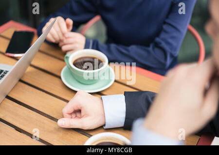 Group of businesspeople, having meeting at cafe, outdoors, mid section Stock Photo