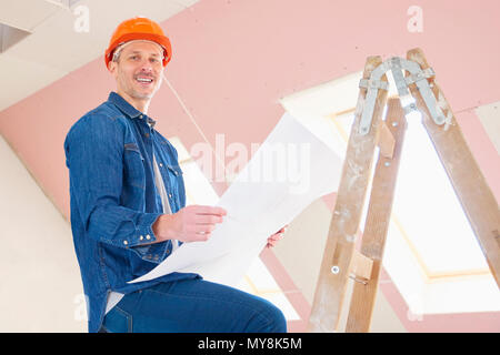 Portrait of construction worker holding plan in his hand while standing on the ladder and working. Stock Photo