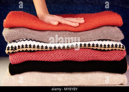 Hand touches warm woolen things neatly stacked in a pile Stock Photo
