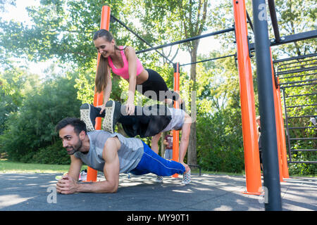 Three friends forming a pyramid while doing push-up and plank exercises Stock Photo