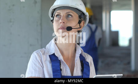 Female construction engineer reading plans and talk to workers through internal links Stock Photo