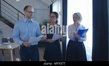 Confident business partners walking down in office building and discussing work Stock Photo