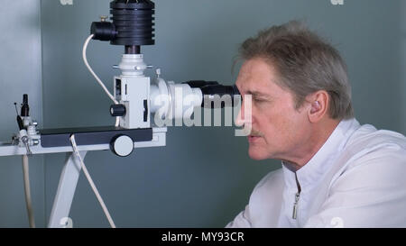 Attentive optometrist examining male patient on slit lamp in ophthalmology clinic Stock Photo