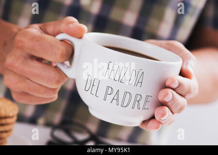 closeup of a caucasian man with a white ceramic cup with coffee in his hands, with the text feliz dia del padre, happy fathers day written in spanish, Stock Photo