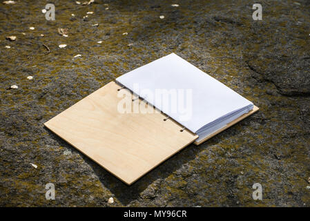 Open diary with a wooden cover lies on the stones Stock Photo