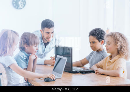 Happy children learn programming using laptops on extracurricular classes Stock Photo