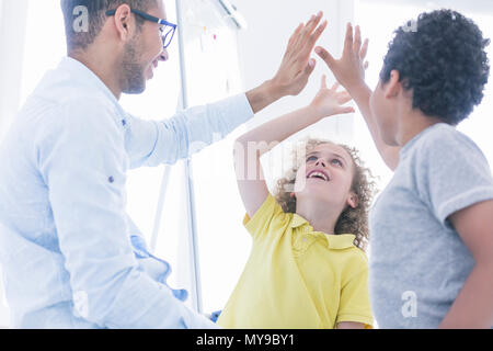 Children playing with computer science teacher in white classroom Stock Photo
