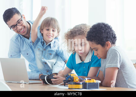 Children and teacher play with robots during modern computer classes Stock Photo
