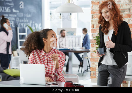 Young women working in creative agency, talking and smiling Stock Photo