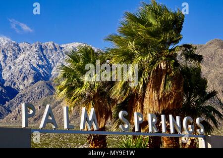 Palm Springs sign in front of palm trees and snow covered mountains Stock Photo