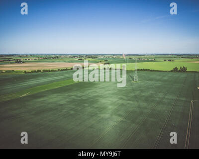 Aerial view of high voltage line over field of green grain Stock Photo