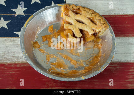 single apple pie slice with lattice crust in aluminum pie pan on wooden American flag Stock Photo