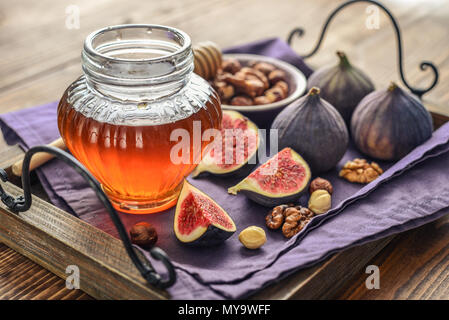 Honey with fresh figs and nuts on tray on wooden background closeup Stock Photo