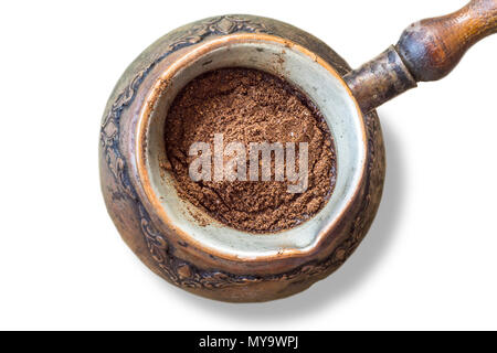An old coffee maker made in the Middle East. Ground coffee is poured into cold water. Turkish coffee . Isolated photo on a white background. Stock Photo