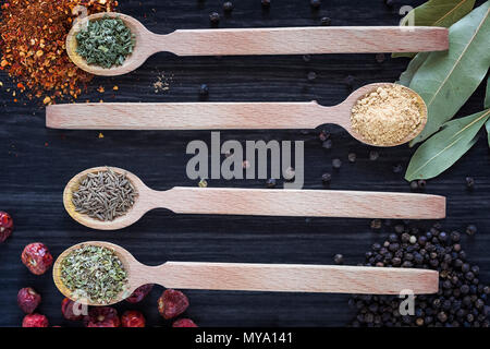 Four wooden spoons with various spices on dark wooden background Stock Photo