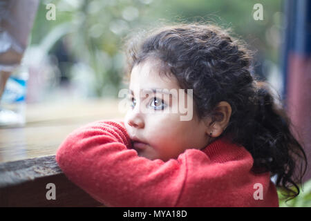 Thoughtful Indian girl looking out through window Stock Photo