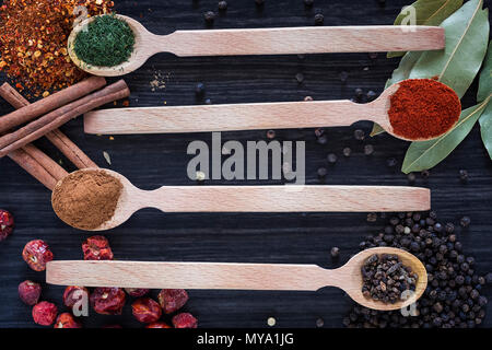 Four wooden spoons with various spices on dark wooden background Stock Photo