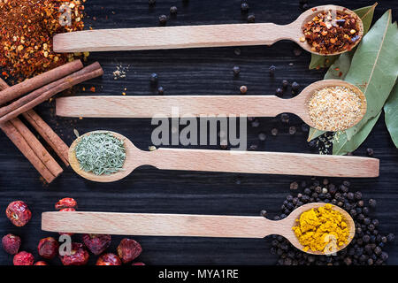 Four wooden spoons with various spices on dark wooden background Stock Photo