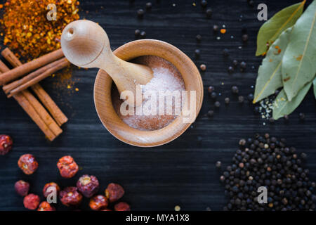 Wooden mortar and various spices on dark wooden background Stock Photo