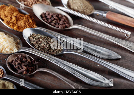 Different spices in  spoons on a old wooden background. Stock Photo