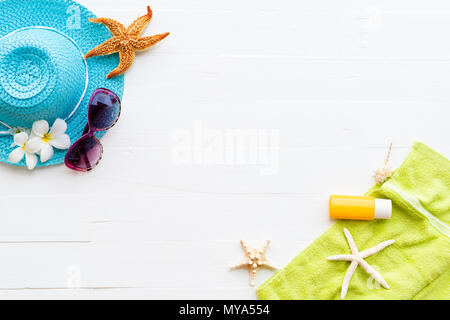 Beach accessories including sunglasses, starfish, hat beach, sunblock, green towel, and sunblock on bright white pastel wooden background for summer h Stock Photo